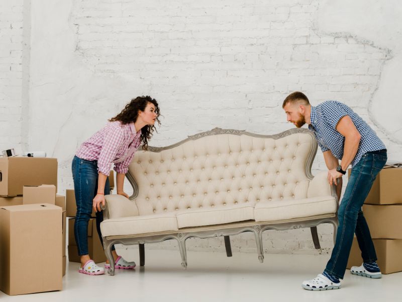 Twee mensen die een bank optillen met spit