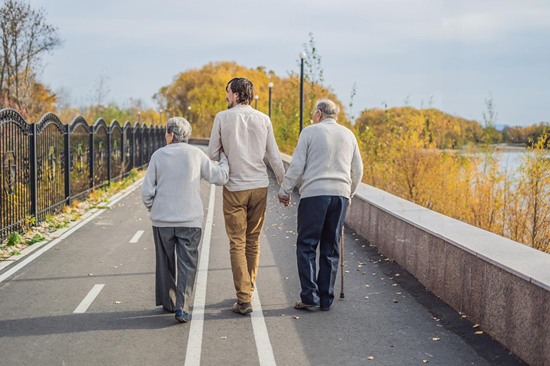 Twee ouderen lopen met een begeleider buiten en werken aan valpreventie voor ouderen